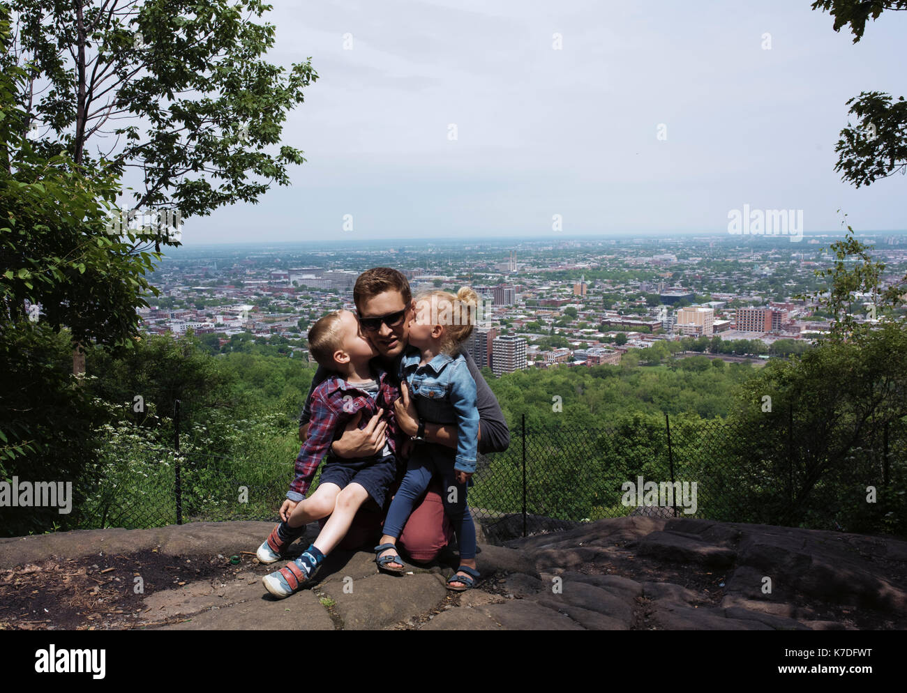 Bambini baciare padre contro cityscape Foto Stock