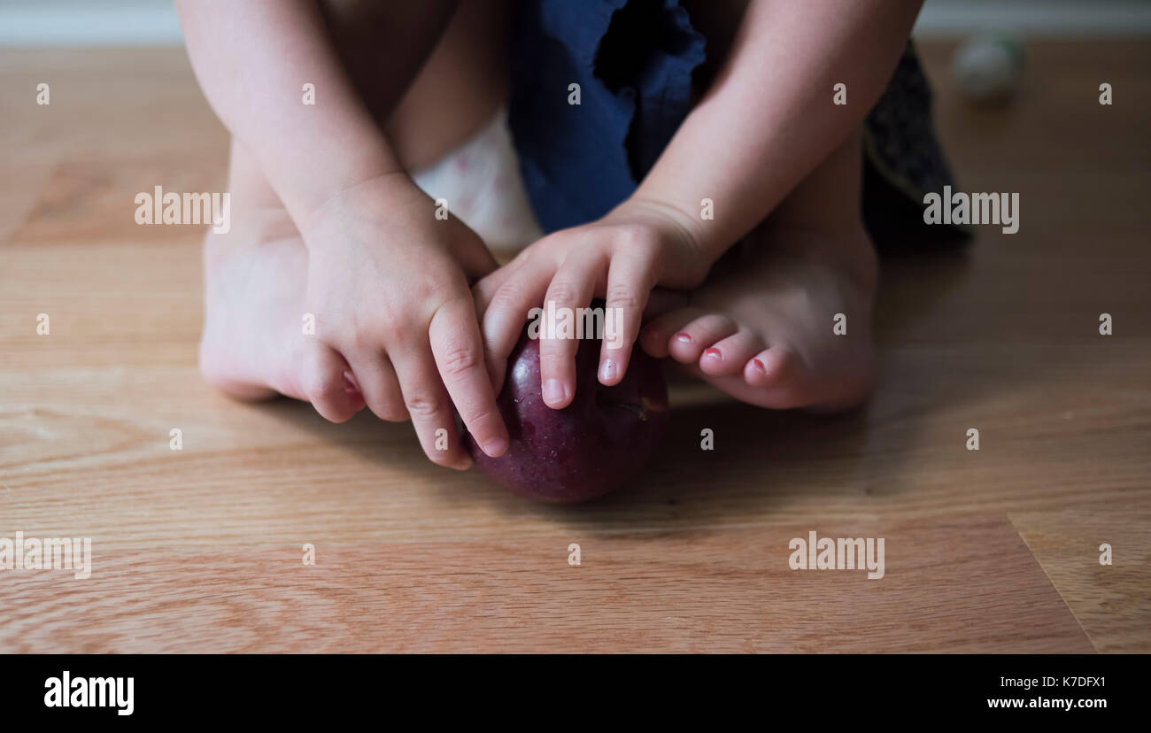 Sezione bassa della ragazza che gioca con Apple a casa Foto Stock