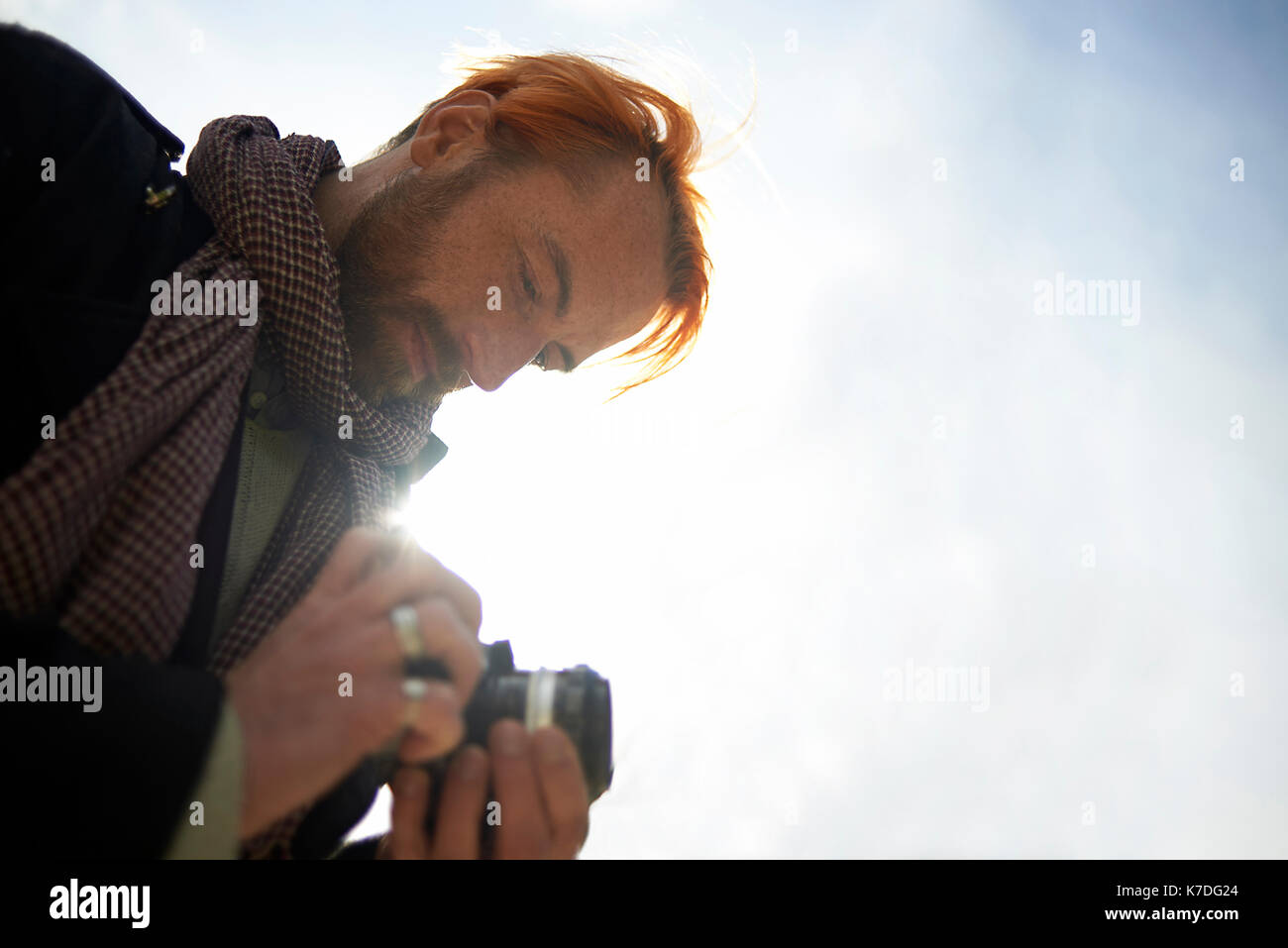 Basso angolo di visione dell'uomo guarda le foto sulla fotocamera DSLR contro sky Foto Stock