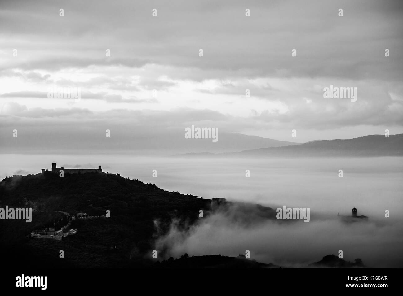 Bellissima vista della città di Assisi (Umbria) da dietro, sopra un mare di nebbia all'alba Foto Stock