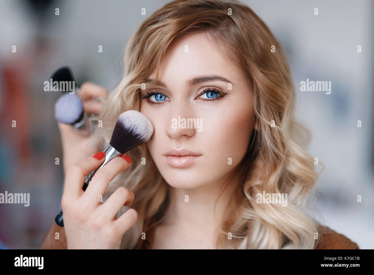 Processo di make-up artist il lavoro con il modello di close-up. bellissima ragazza con gli occhi blu Foto Stock
