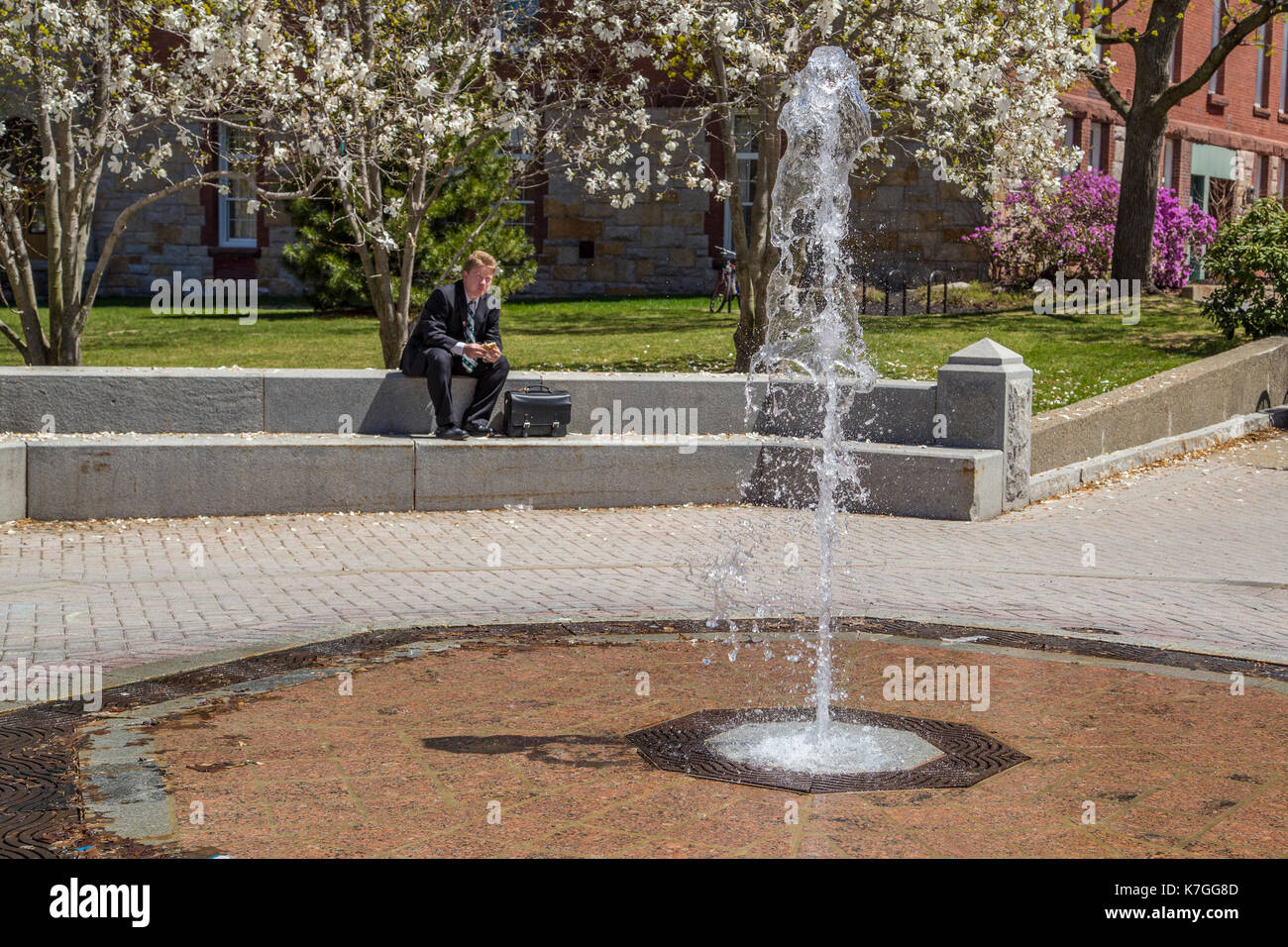 Uomo seduto accanto a una fontana di Worcester, Massachusetts Foto Stock