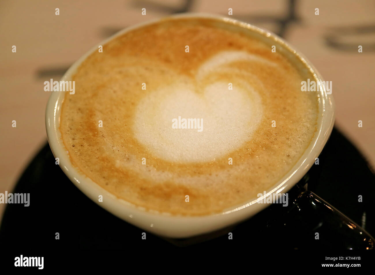 A forma di cuore in schiuma di caffè di cappuccino caldo con il fuoco selettivo Foto Stock