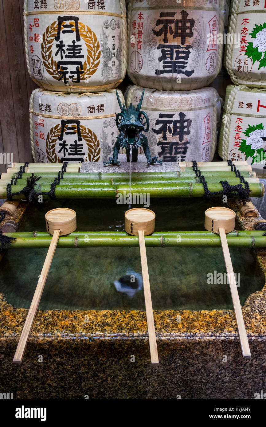 Kyoto, Giappone - 16 maggio 2017: fila di mestoli in un bacino purificaton con un drago gargoyle vicino al tempio Shintoista Foto Stock