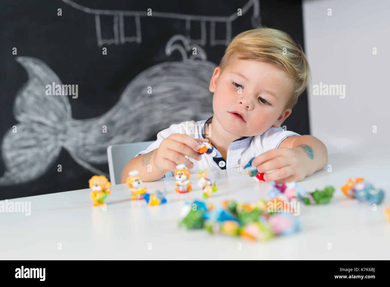 Ritratto di carino toddler boy giocare con giocattoli alla scrivania a casa. Foto Stock