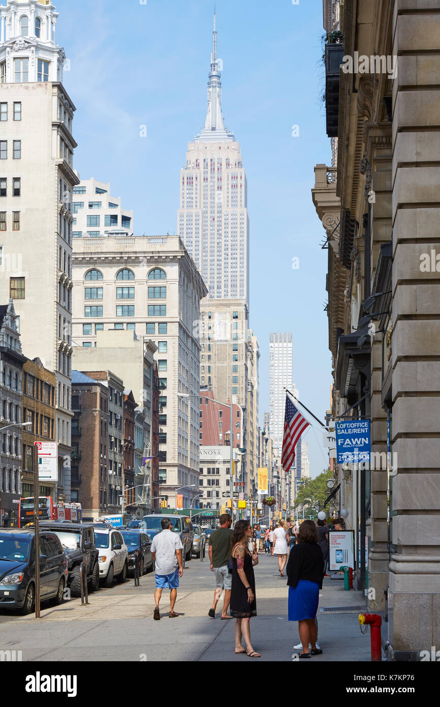 Empire State Building e la Quinta Avenue marciapiede con persone in una giornata di sole in New York Foto Stock