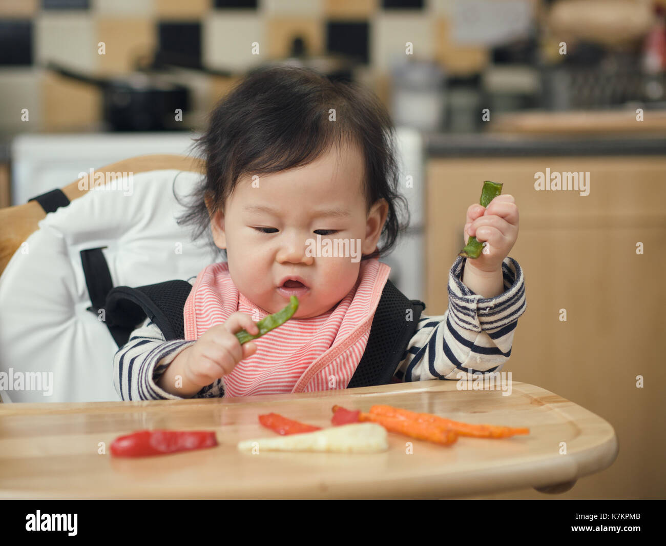 Asian Baby girl mangiando verdure arrosto alla cucina domestica Foto Stock