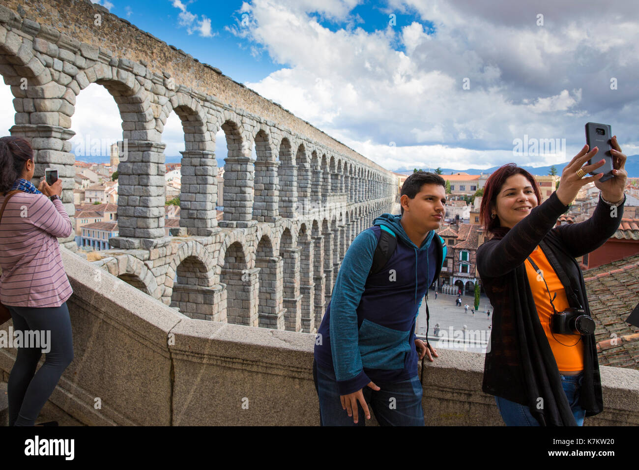 I turisti tenendo selfie fotografie con lo smartphone al famoso spettacolare acquedotto romano di Segovia, Spagna Foto Stock