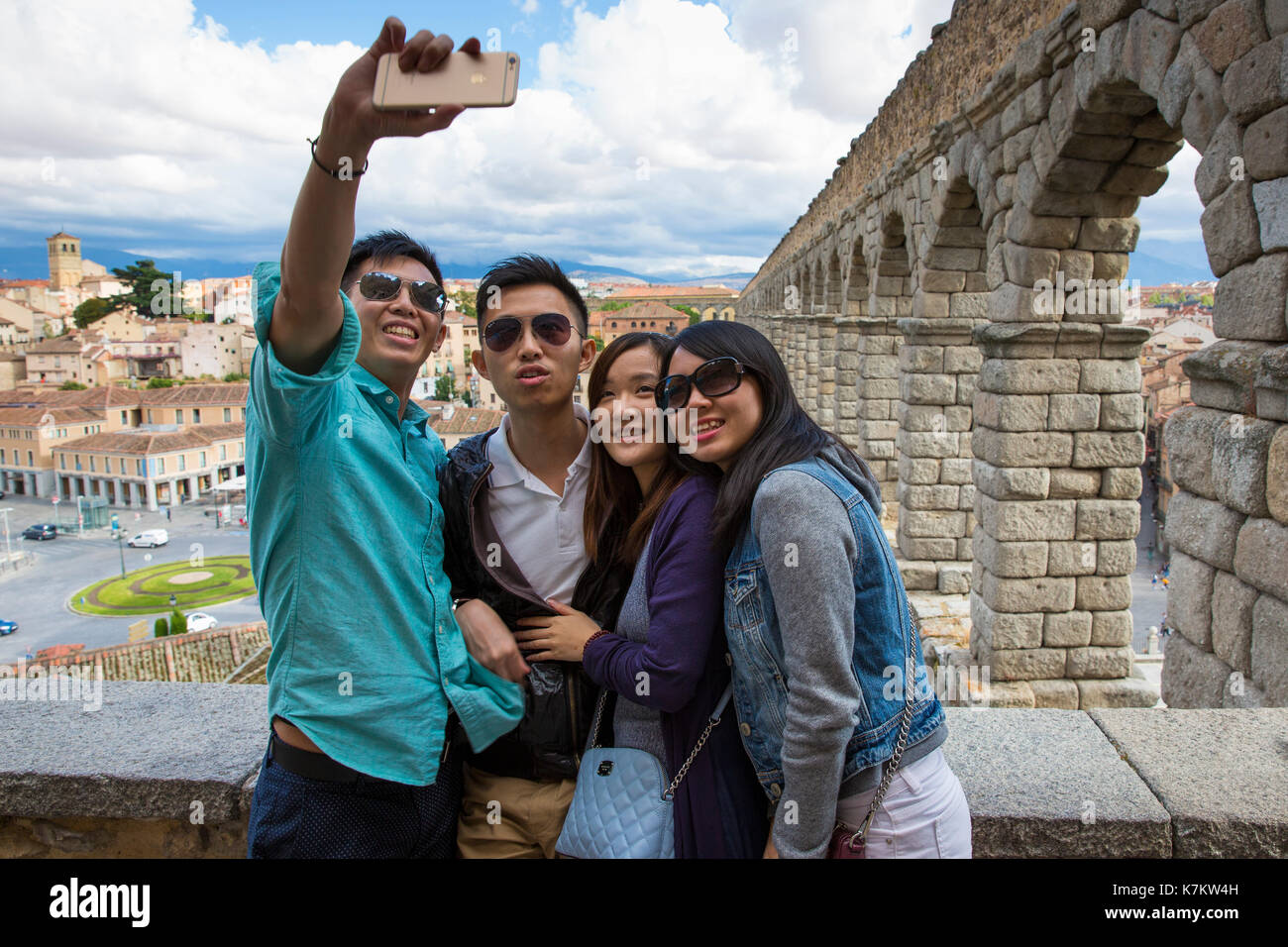 Giovani turisti cinesi tenendo selfie fotografie con iphone smartphone a famoso acquedotto romano di Segovia, Spagna Foto Stock