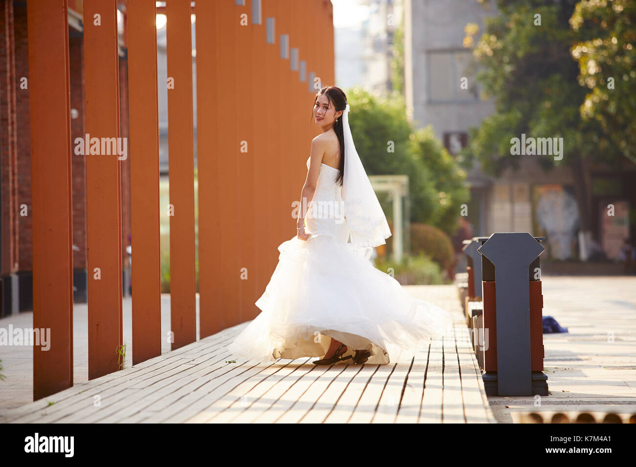 Outdoor Ritratto di giovane e bella asiatica sposa con bouquet in mano. Foto Stock