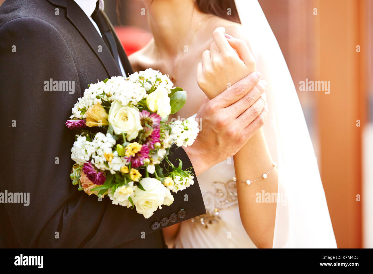 Amare la sposa e lo sposo con bouquet che abbraccia ogni altra al giorno di nozze Foto Stock