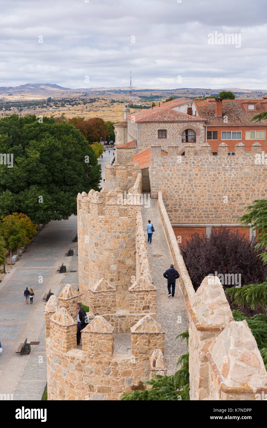 I turisti passeggiano lungo la parte superiore delle mura medievali della città di Avila, Spagna Foto Stock