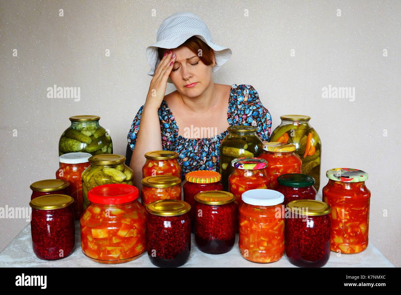 Triste donna con mal di testa si siede con conserve fatte in casa Foto Stock