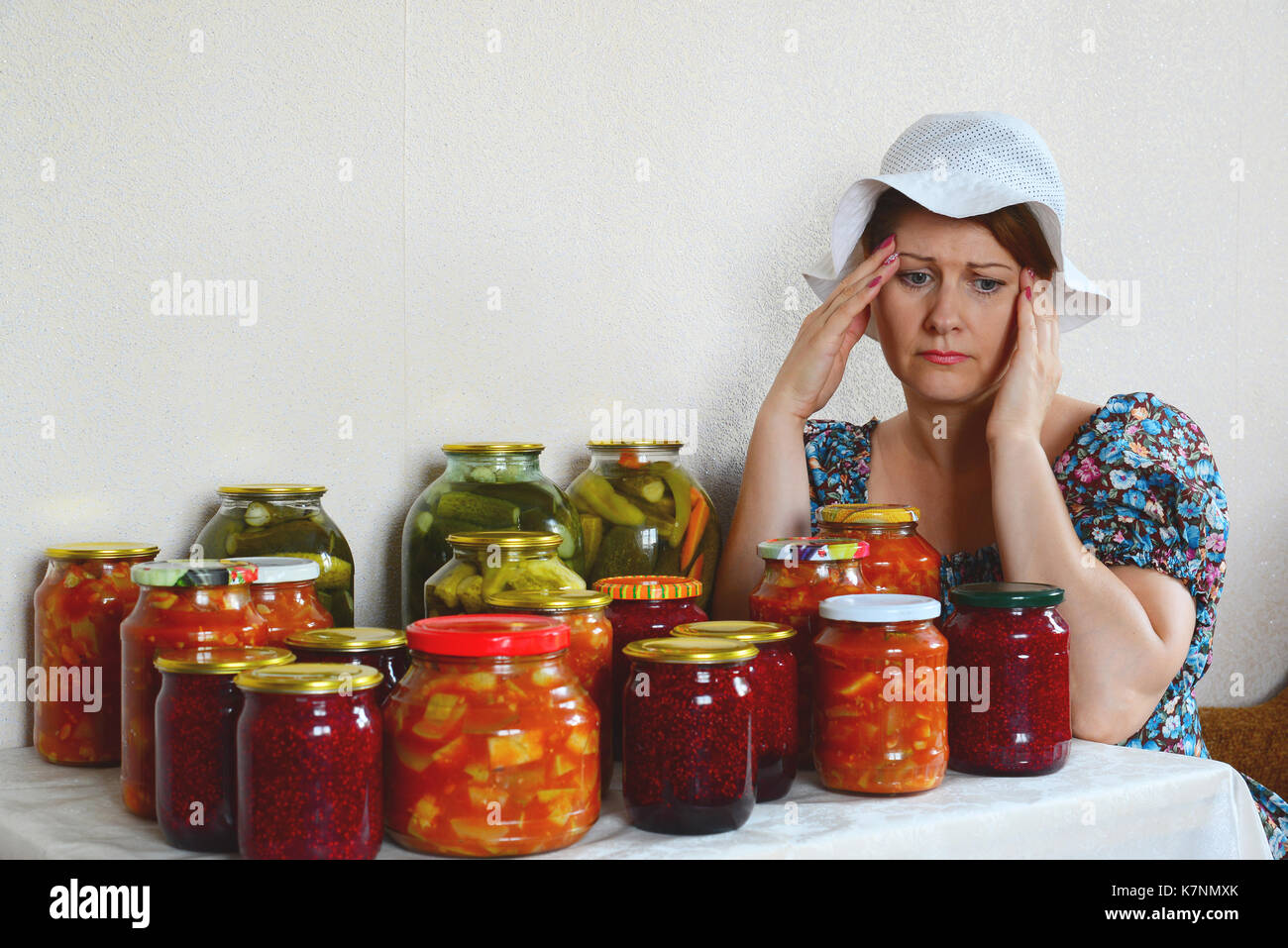 Triste donna con mal di testa si siede con conserve fatte in casa Foto Stock