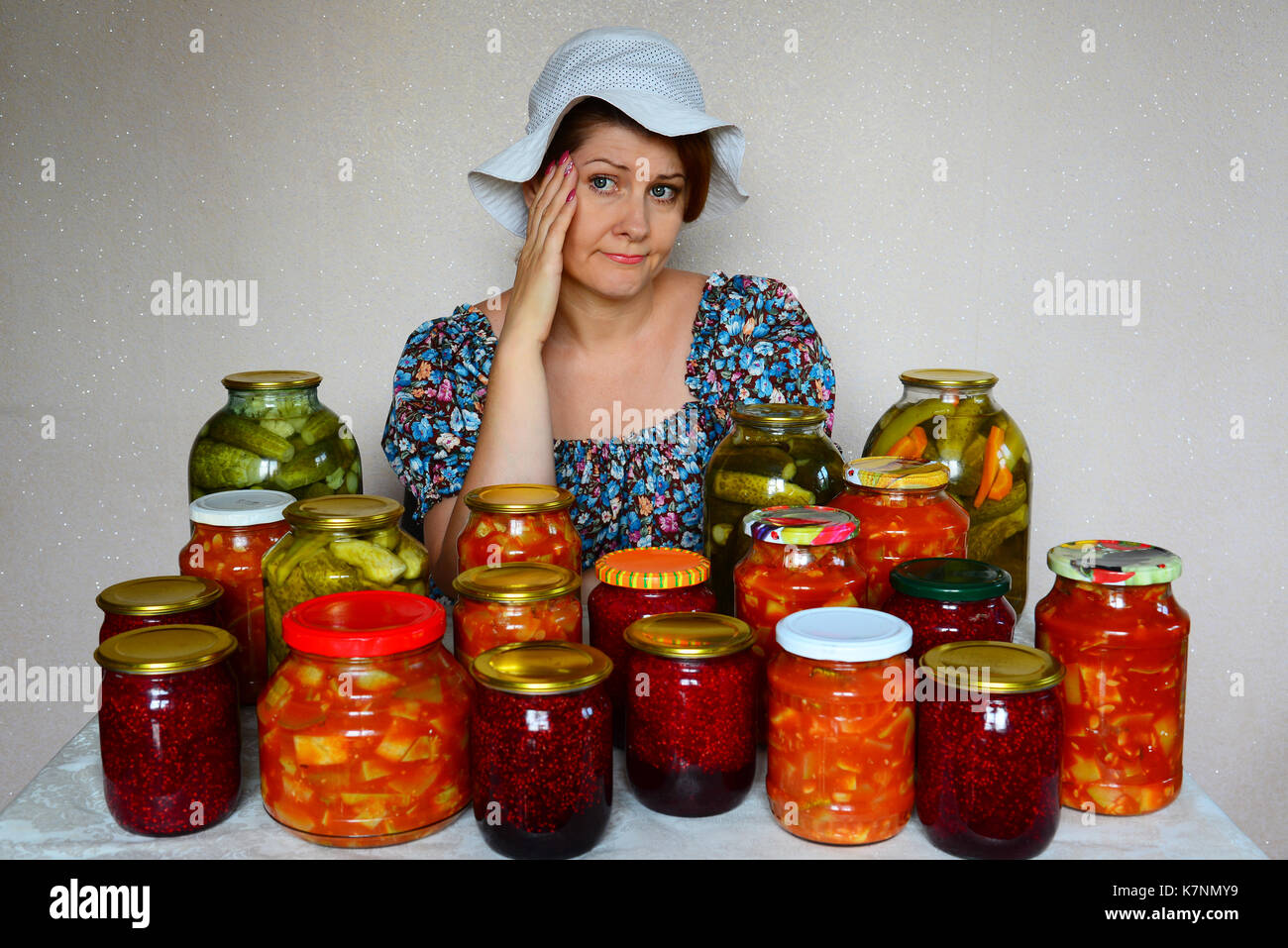Triste donna si siede con conserve fatte in casa Foto Stock
