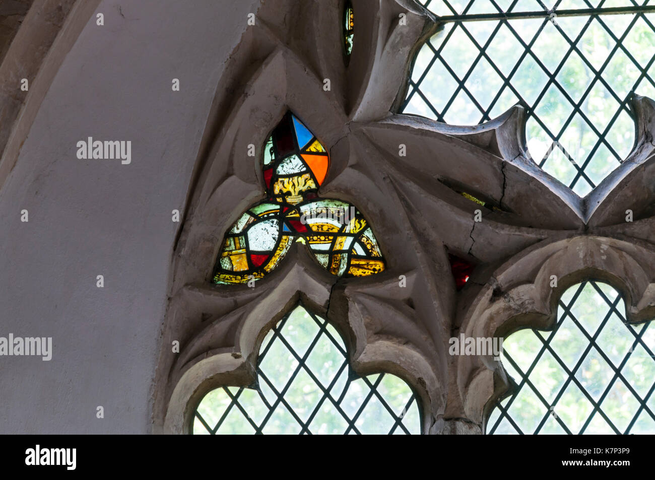 Frammenti medievali di vetro macchiato nel XIV secolo reticolato finestra tracery presso il St Peter & St Paul Church, Newchurch su Romney Marsh, Kent. Foto Stock