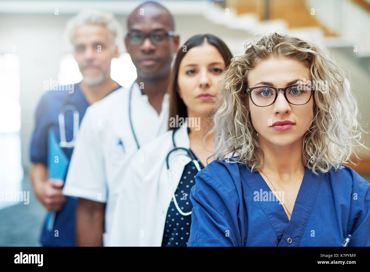 Malinconici team di medici guardando la fotocamera in piedi in un ospedale. Foto Stock