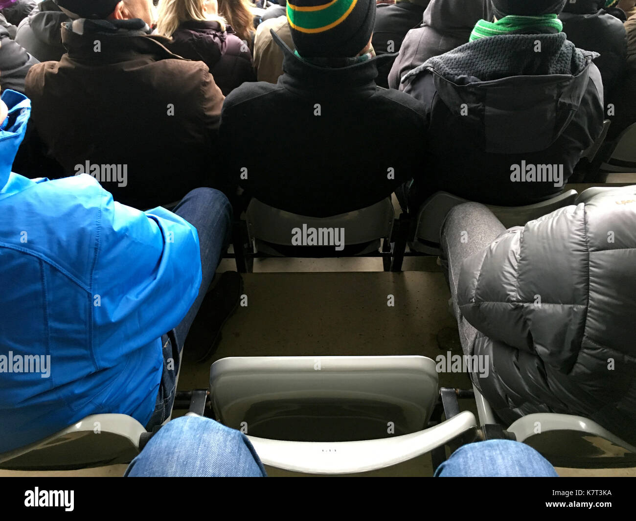 Una solitaria il sedile rimane tra una folla di tifosi in uno stadio sportivo indicando una ventola mancante sul gioco o metafora per FOMO Foto Stock