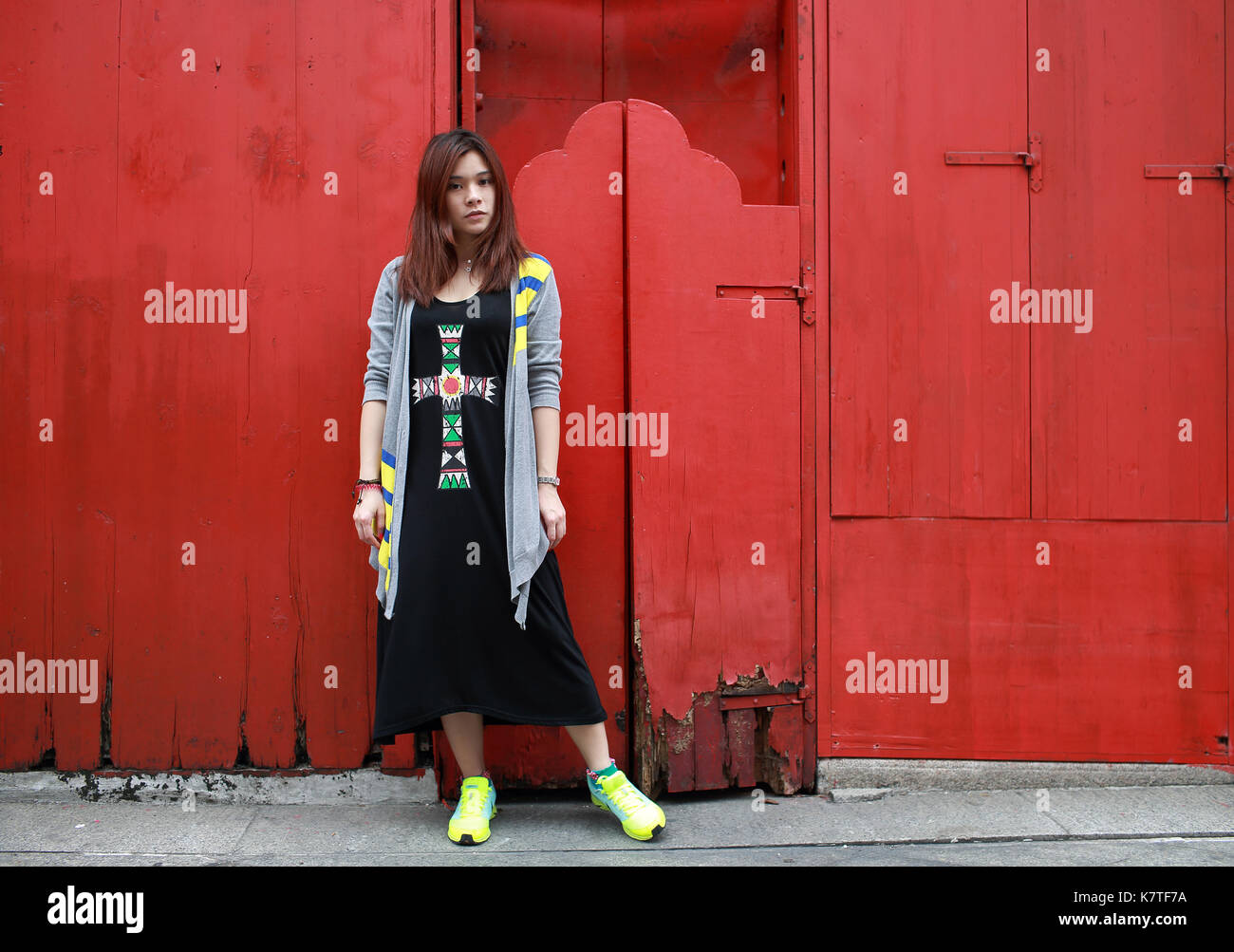 Ragazza sulla strada con sfondo rosso vecchio cancello cinese nella città vecchia di Macao Foto Stock
