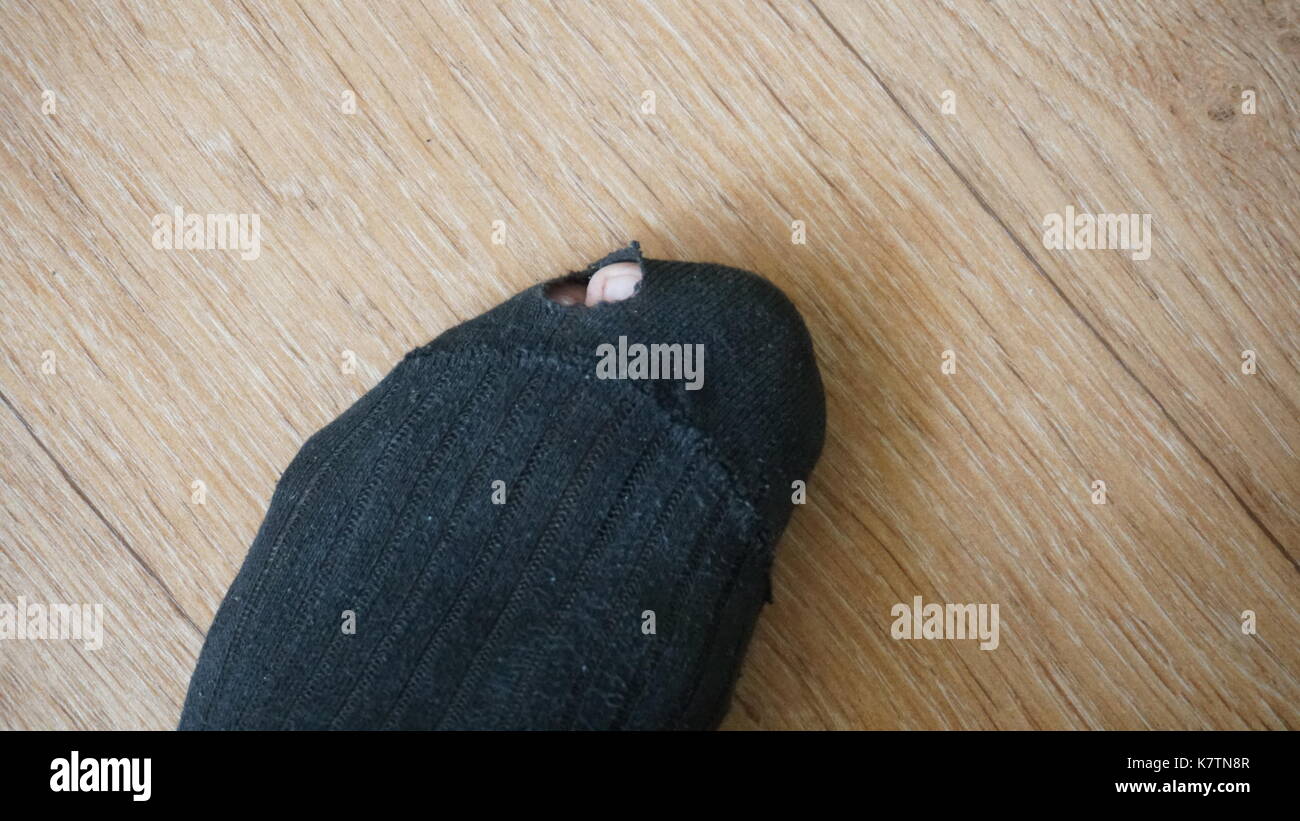 Metafora concettuale, due calze di lana, uno con il foro e un alluce sporgente. pannolino vecchie calze di lana. Foto Stock