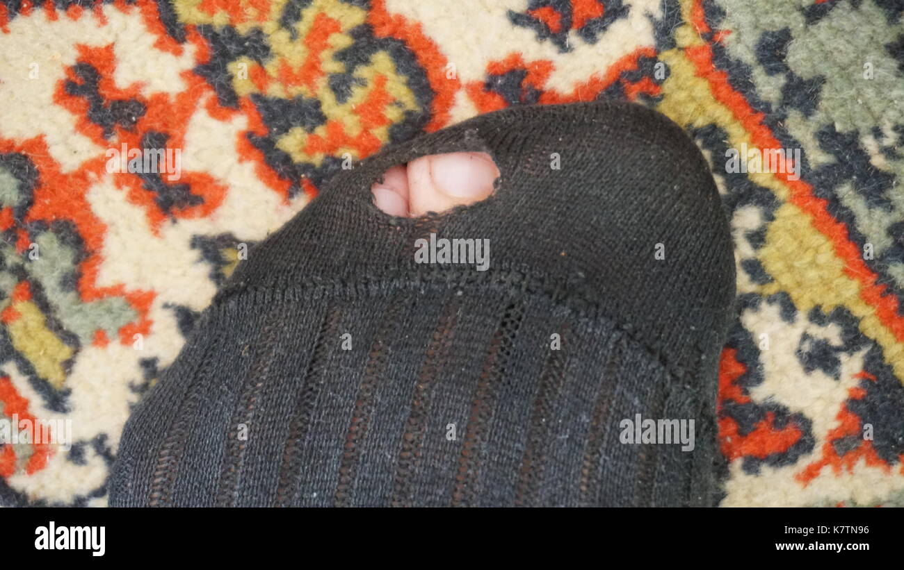 Metafora concettuale, due calze di lana, uno con il foro e un alluce sporgente. pannolino vecchie calze di lana. Foto Stock