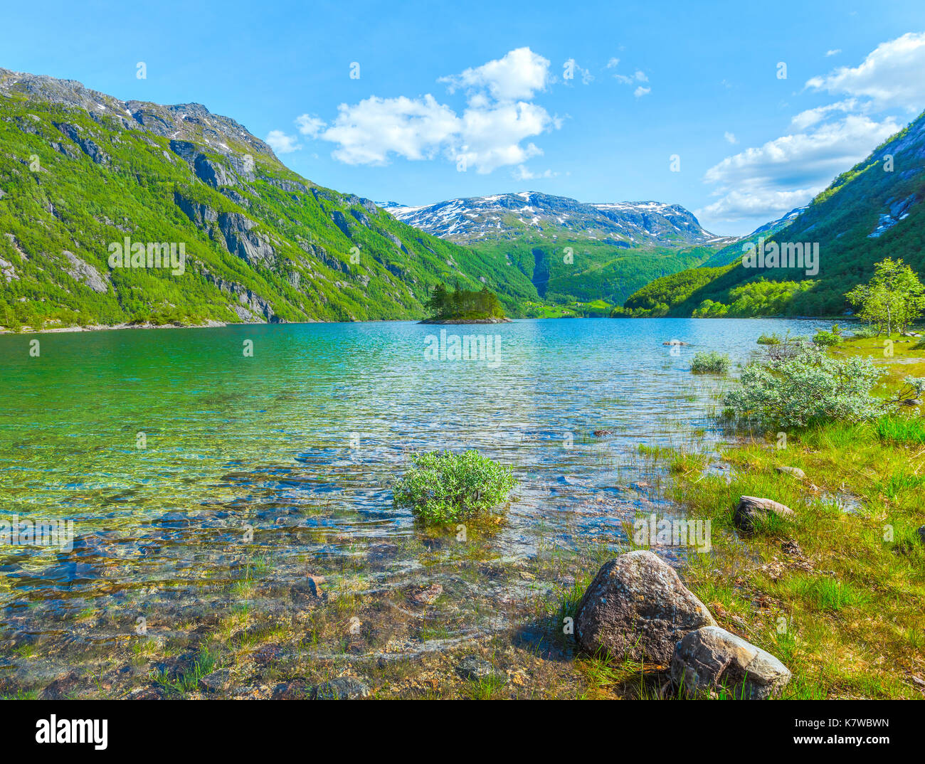 Lago Roldalsvatnet in Norvegia, con la piccola isola e visualizzare in villaggio Boten e delle montagne innevate, Roldal in Norvegia e Scandinavia Foto Stock