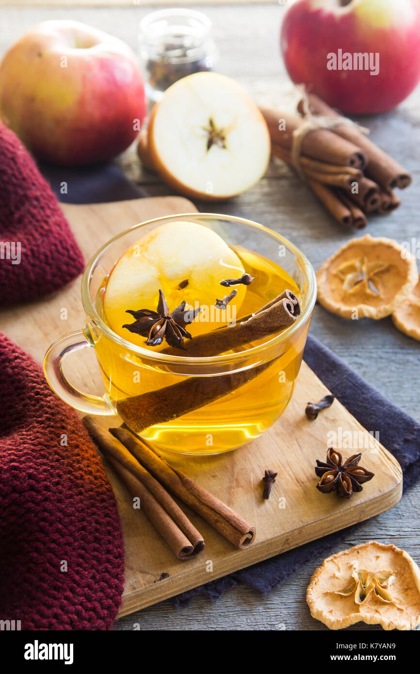 Bevanda calda (apple tè, punch) con bastoncino di cannella, anice stellato e chiodo di garofano. stagionale drink mulled su sfondo di legno. bevanda calda con mele per autunno o Foto Stock