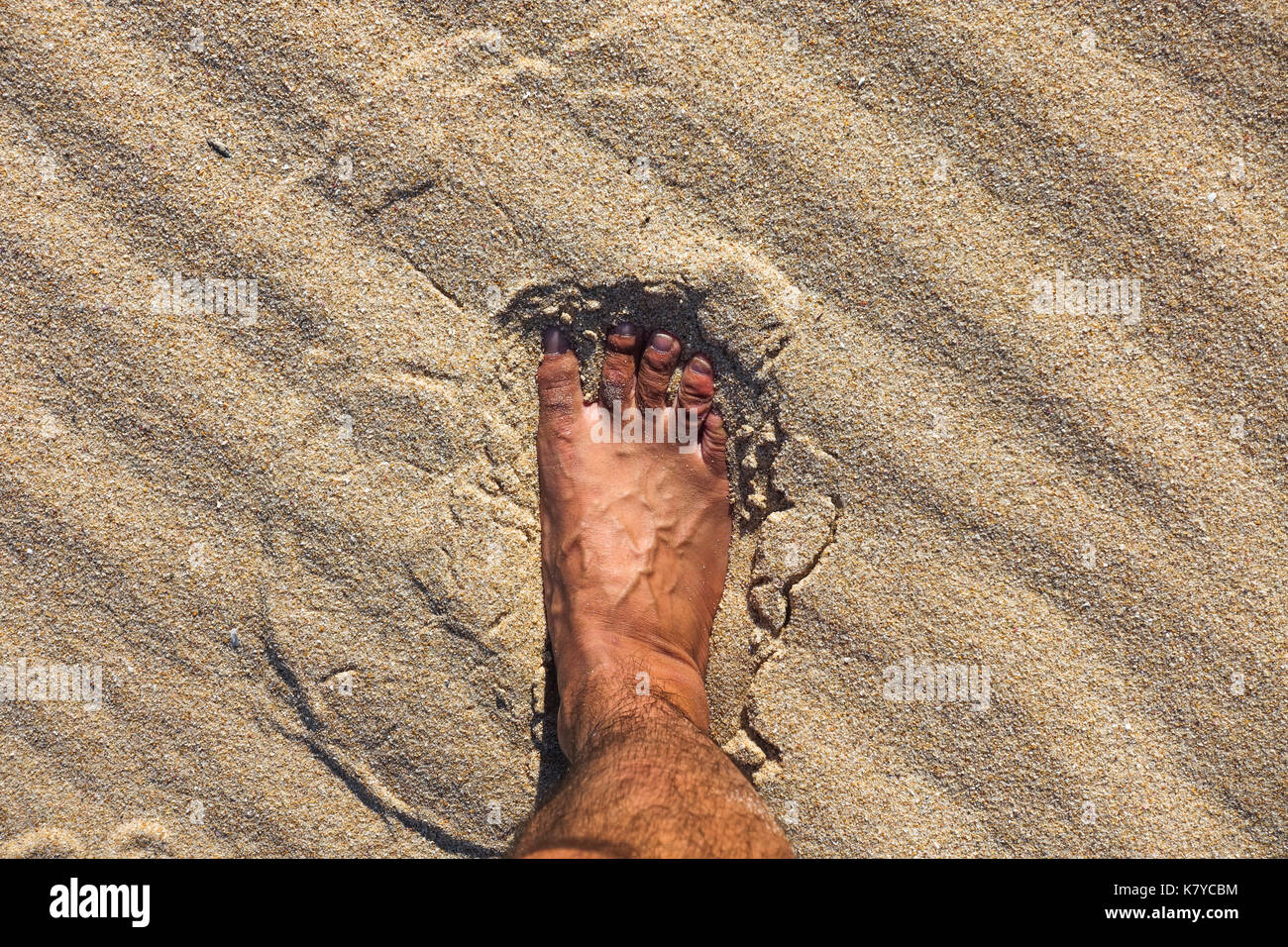 Piede dell uomo sulla calda sabbia della spiaggia spagnola, Spagna. Foto Stock
