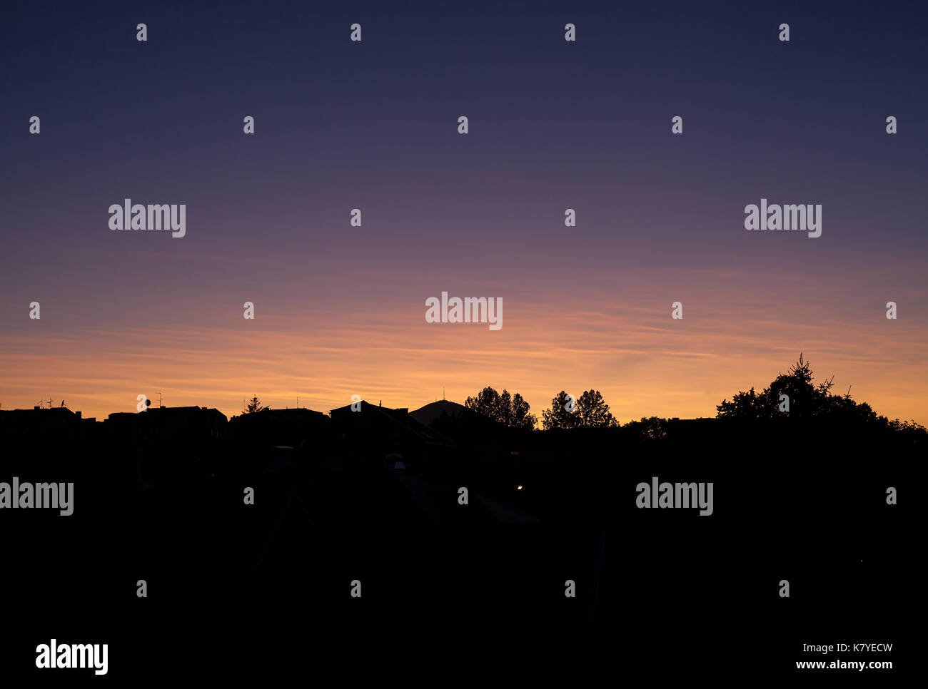 Tramonto in città e colorati di cielo sopra le forme di costruzione di tetti e alberi. Foto Stock