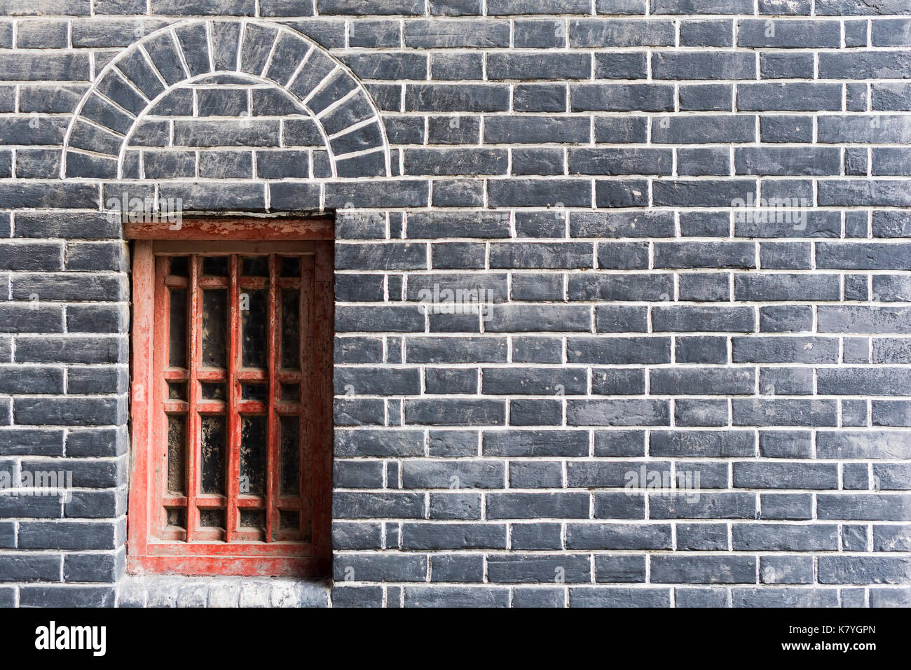 Piccola finestra rossa in un muro di mattoni Foto Stock