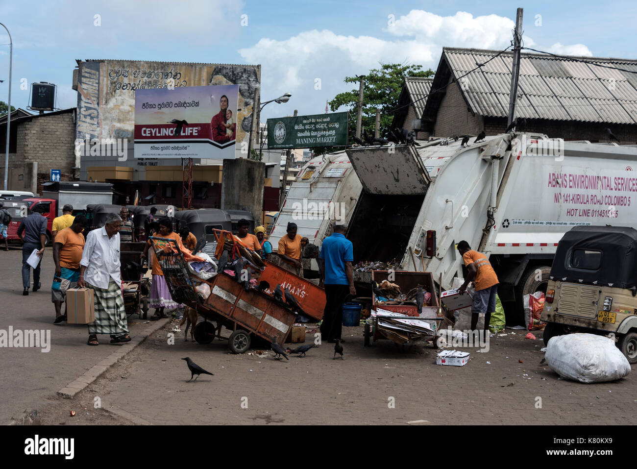 I mercatili ripuliscono i rifiuti in attesa di carretti di polvere in un piccolo mercato alimentare nel centro di Columbo in Sri Lanka. Foto Stock