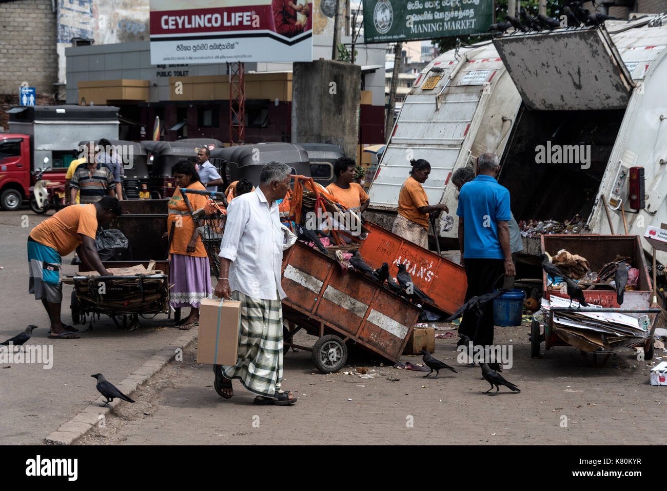 I mercatili ripuliscono i rifiuti in attesa di carretti di polvere in un piccolo mercato alimentare nel centro di Columbo in Sri Lanka. Foto Stock