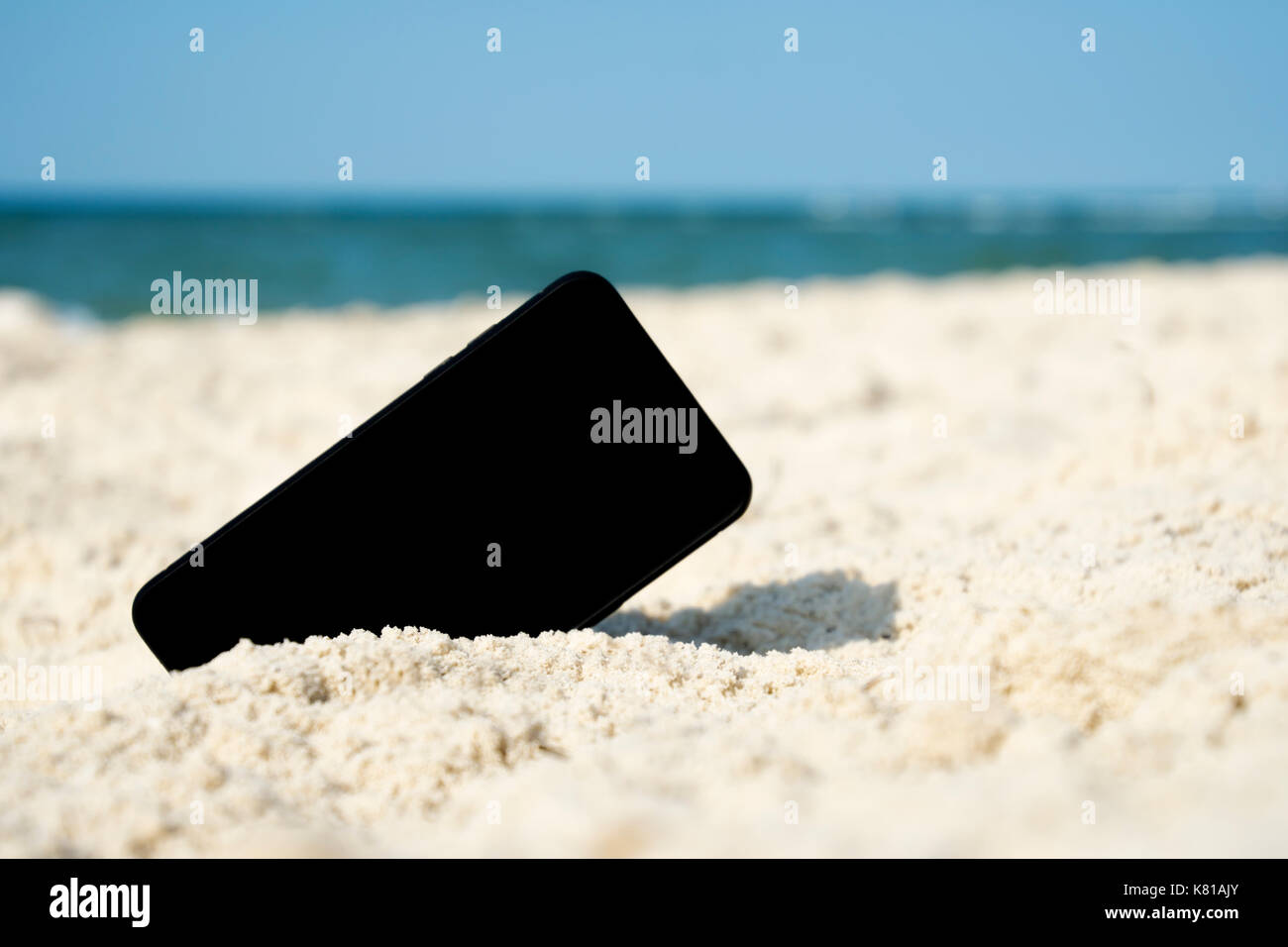 Mobile touch telefono in sabbia sulla spiaggia Foto Stock