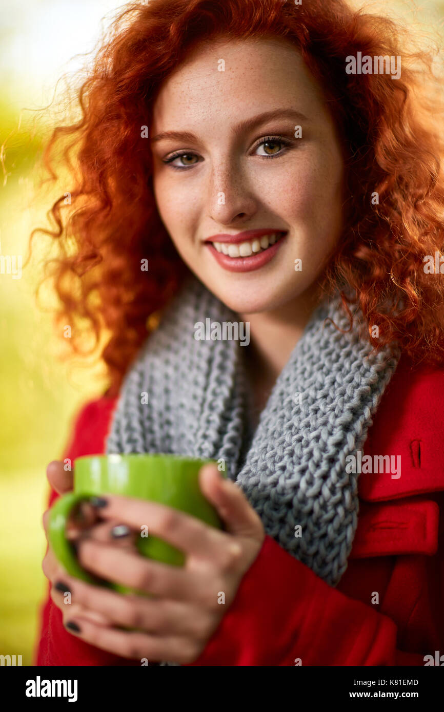 Donna che mantiene tazza di tè nel parco in autunno Foto Stock