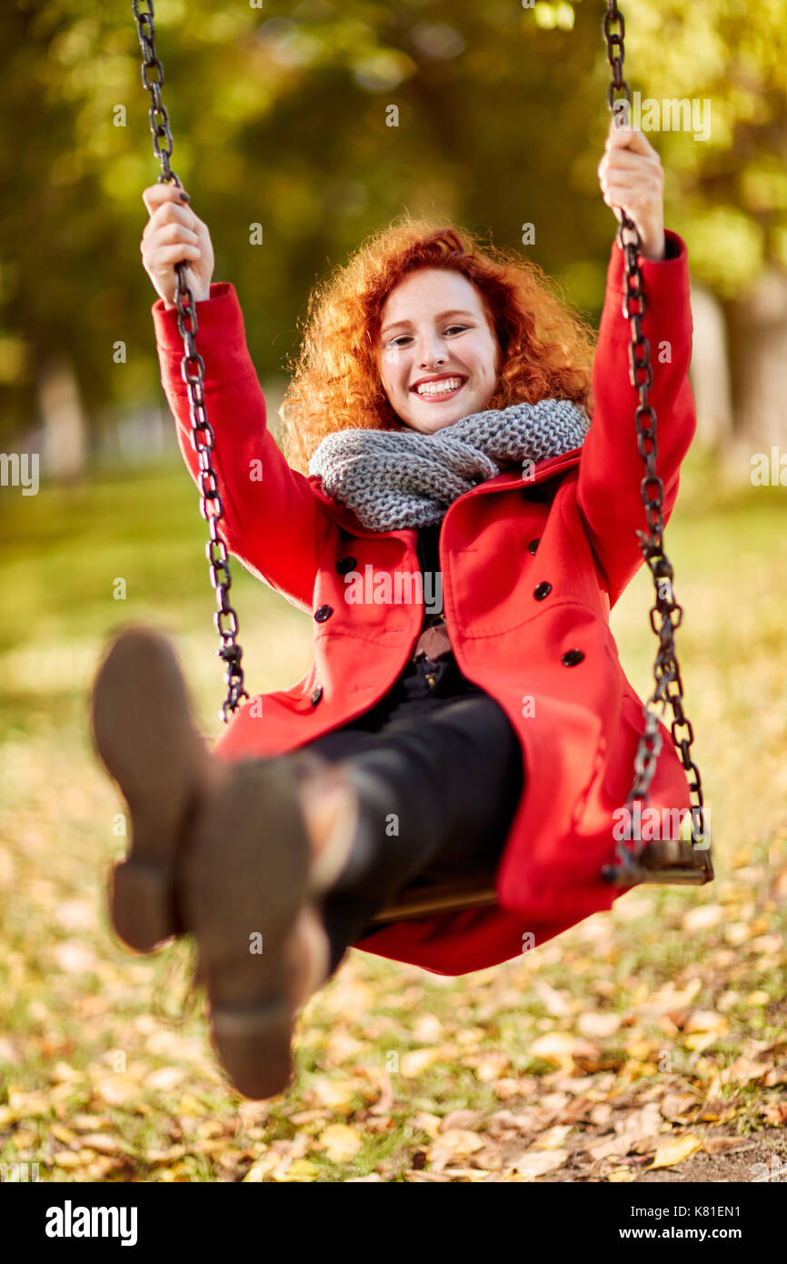 Felice parentesi ginger girl su swing in posizione di parcheggio Foto Stock