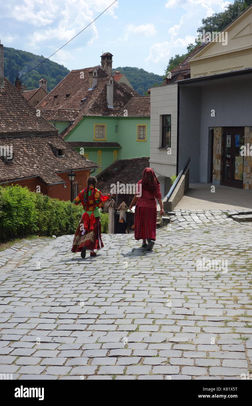 Gypsy camminando in sighisoara città collinare di strade con la loro originale architettura medievale. Transilvania, Romania Foto Stock