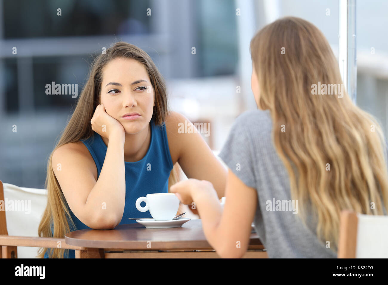 Annoiato ragazza ascoltando una brutta conversazione seduti in un ristorante con terrazzo Foto Stock