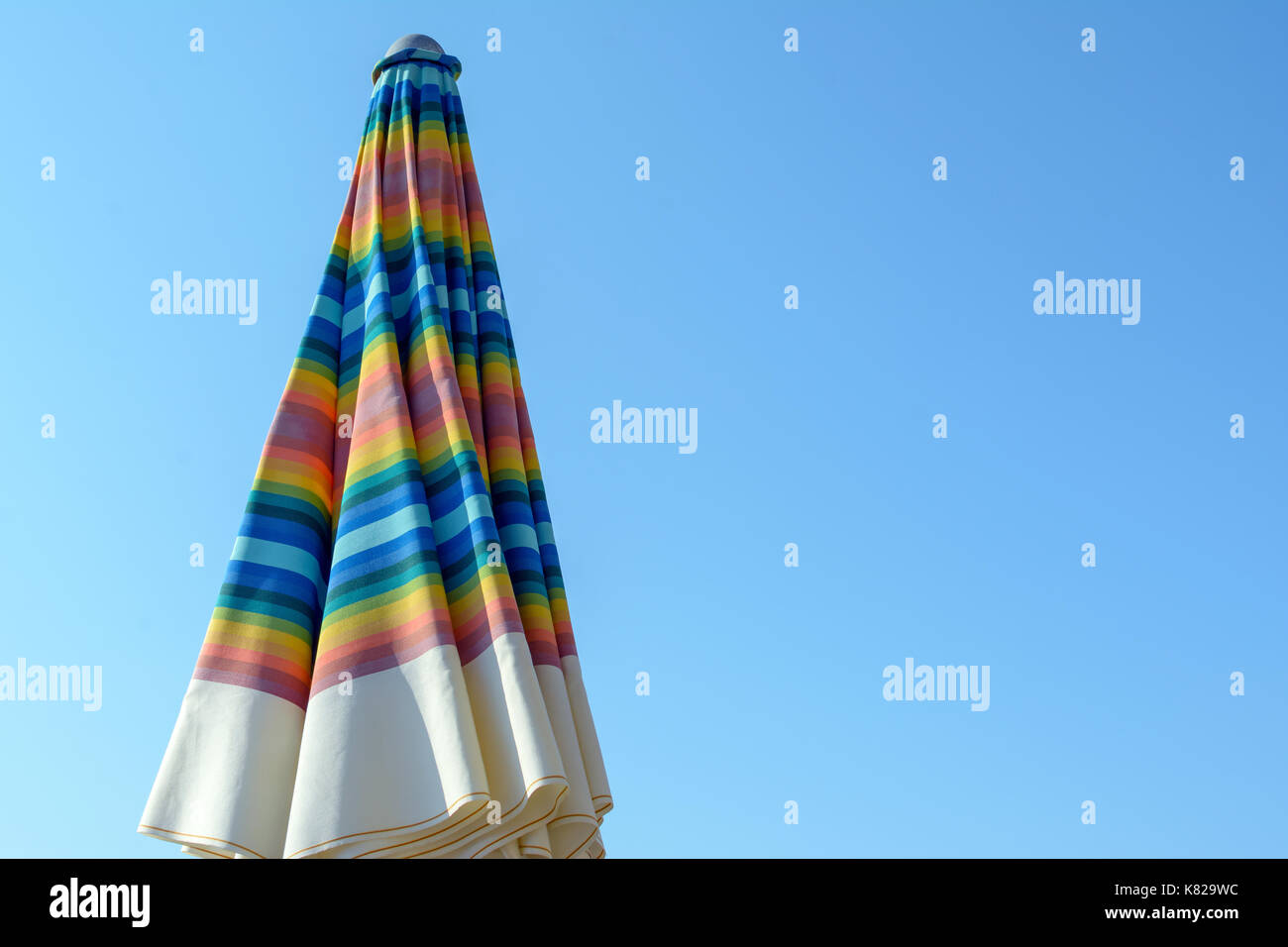 Giornata di relax in spiaggia sotto il colorato ombrellone in riva al mare Foto Stock