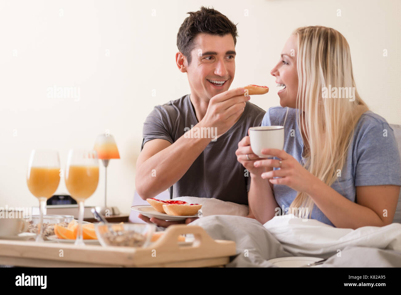 Felice coppia giovane avente la colazione a letto Foto Stock