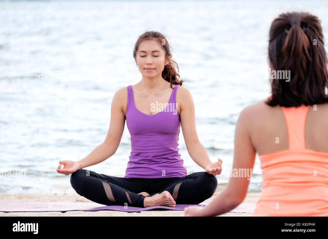 Yoga classe a mare spiaggia ,guru master facendo lotus pongono con valve relax emozione di fronte studente ,meditazione pongono,wellness e sano equilibrio lifest Foto Stock