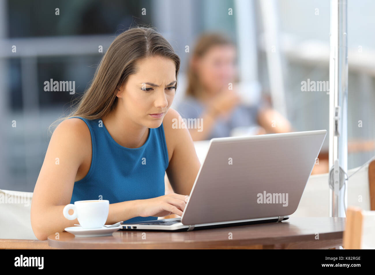 Preoccupati singola donna che utilizza un computer portatile seduto in un bar terrazza Foto Stock