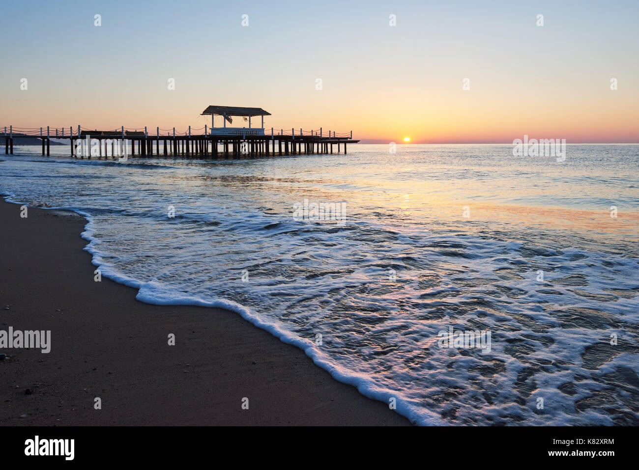 Gazebo sul molo in legno in mare con il sole al tramonto Foto Stock