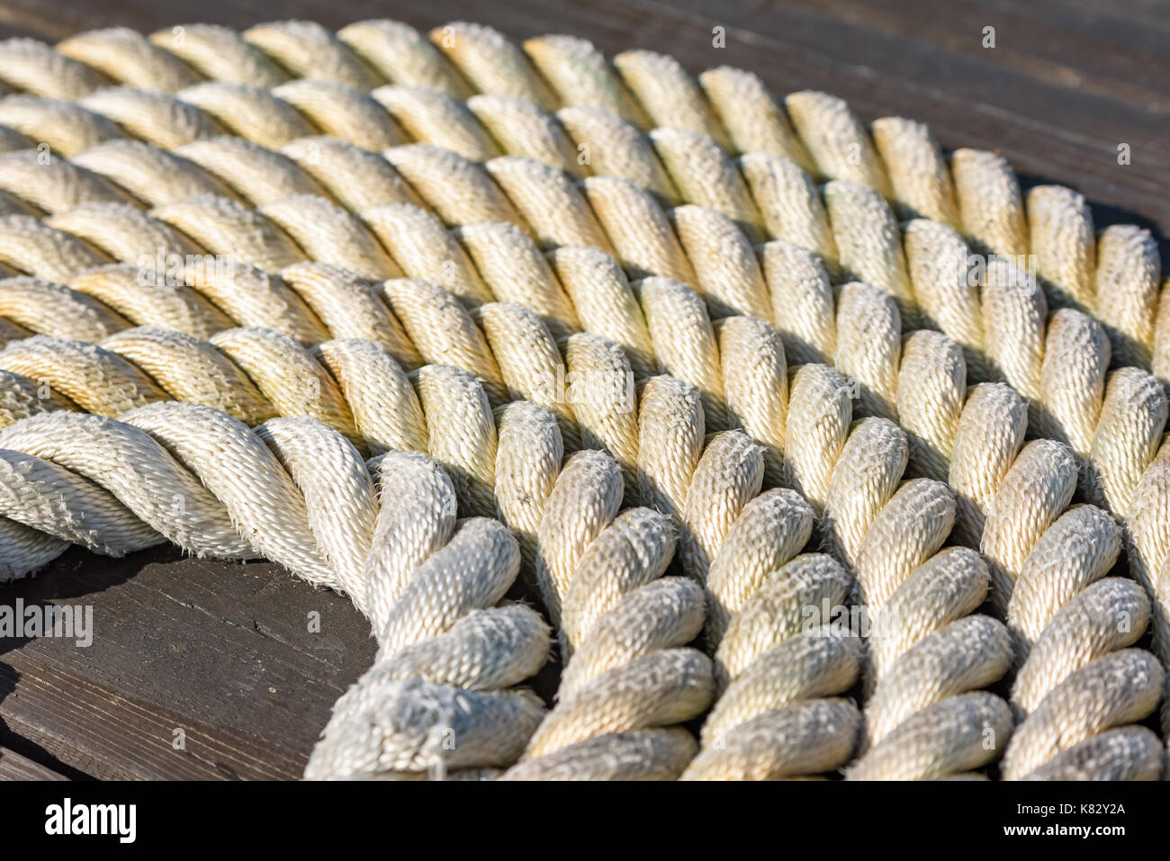 Cima nautica arrotolato a spirale sul molo in legno. Foto Stock