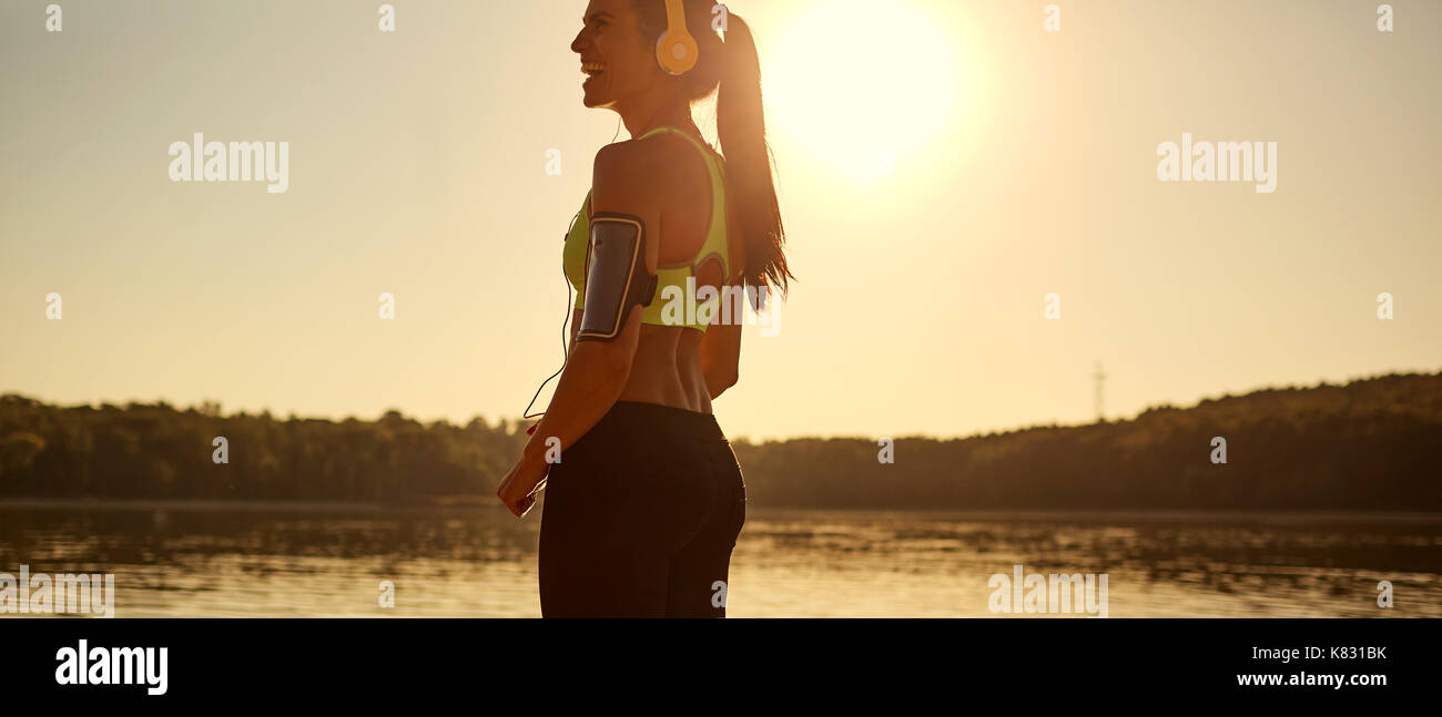 Ragazza sportiva runner ridere al tramonto nel parco. Foto Stock