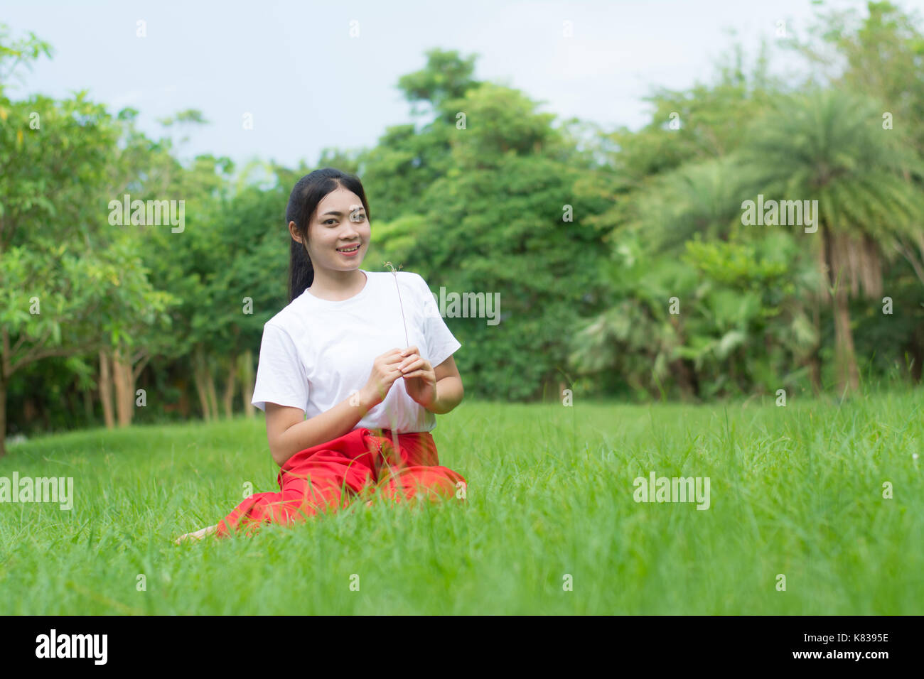 Asian ragazza giovane imparare danza thailandese. La danza classica in maglia bianca rosso perizoma, dimostrare la danza nel giardino Foto Stock