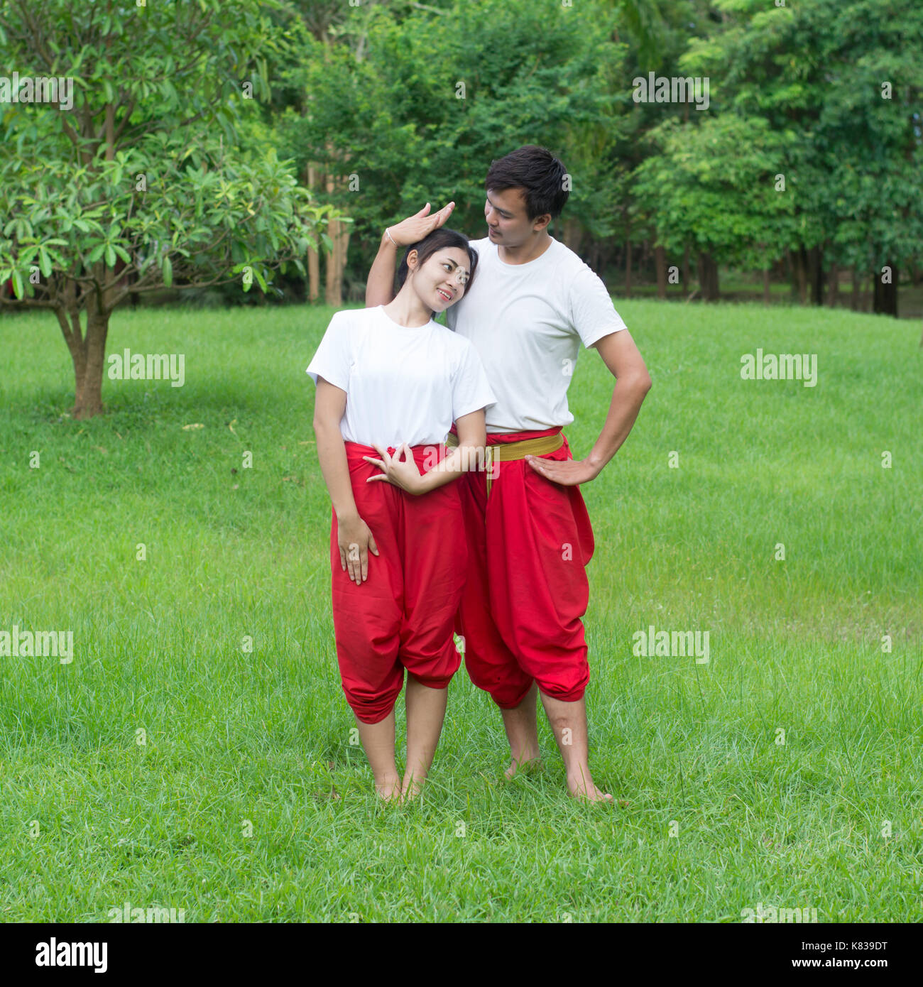 Asian giovane ragazzo e ragazze imparare danza thailandese. La danza classica in maglia bianca rosso perizoma, dimostrare la danza nel giardino Foto Stock