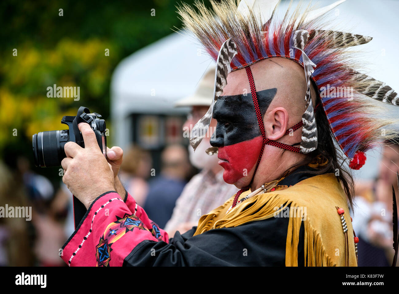Guerriero indigeno del Canada, nativo maschile, Wahta Mohawk/Irochesi che utilizza una fotocamera reflex digitale Canon per fotografare un incontro Pow Wow a Londra, Ontario, Canada. Foto Stock