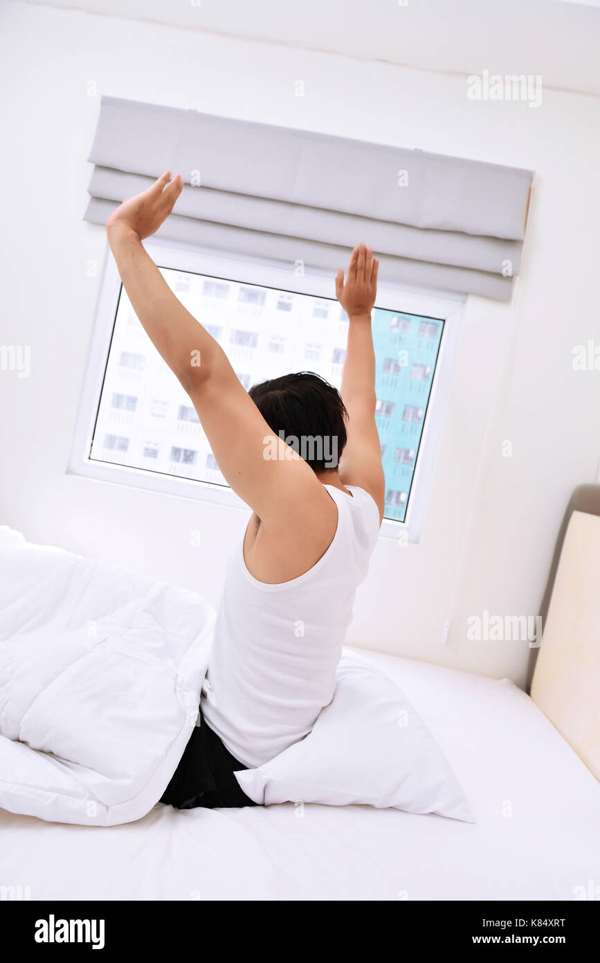 Giovane uomo asiatico il risveglio e stirando le braccia al mattino Foto Stock