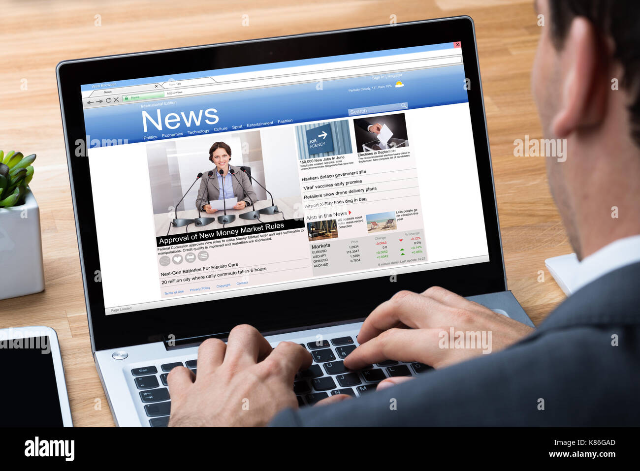 Immagine ritagliata di imprenditore per leggere le notizie sul portatile in ufficio Foto Stock