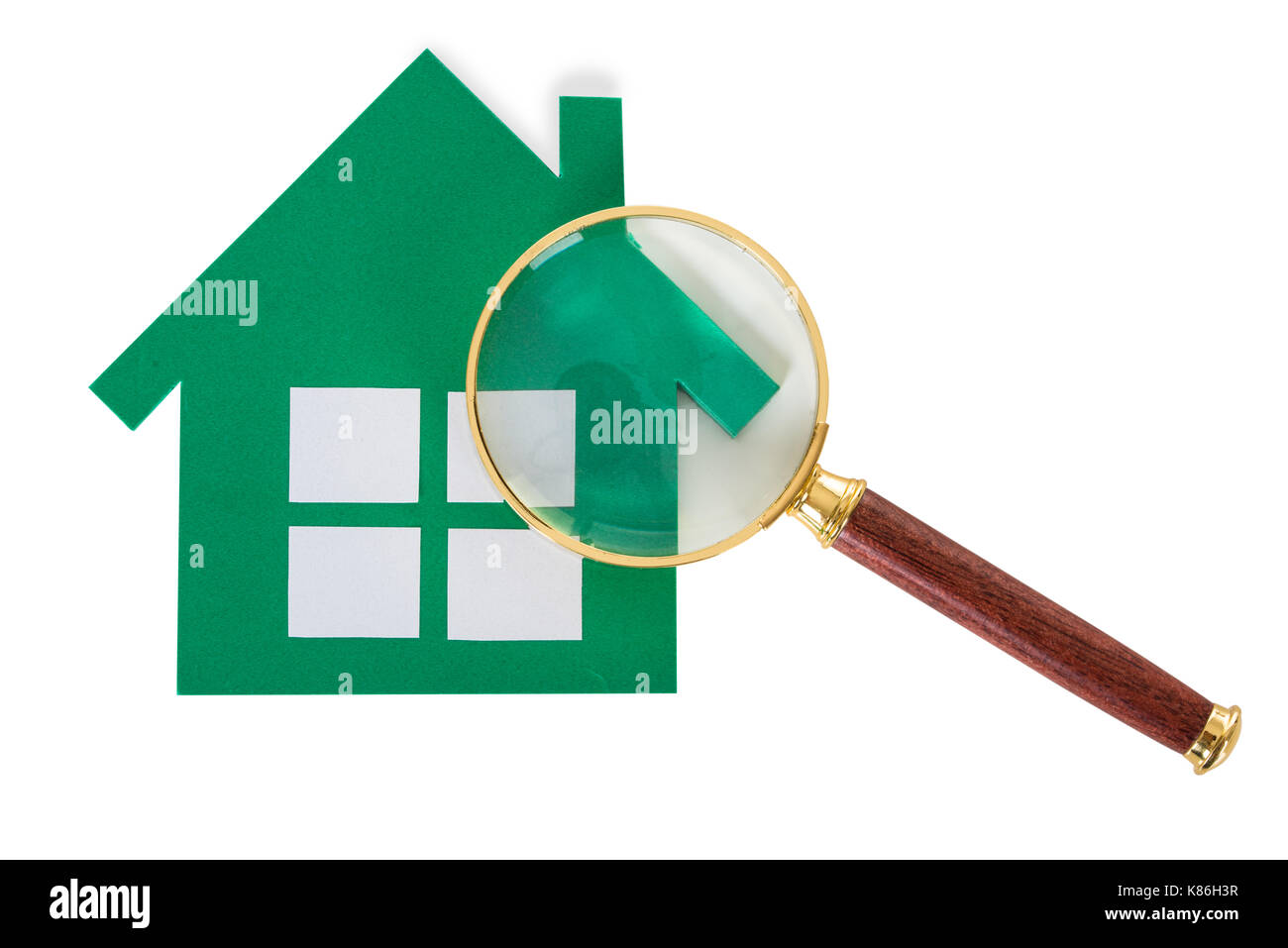 Primo piano della lente di ingrandimento e libro verde casa su sfondo bianco Foto Stock
